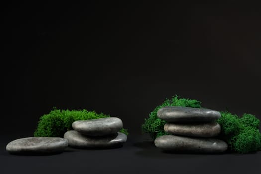 Stones decorated with green moss against black background