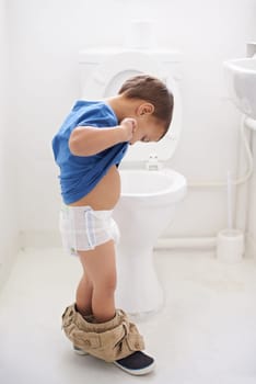 Boy child, potty training and toilet with thinking, diaper and pants on floor for learning, development and progress. Kid, family home and bathroom with ideas, problem solving or solution in nappy