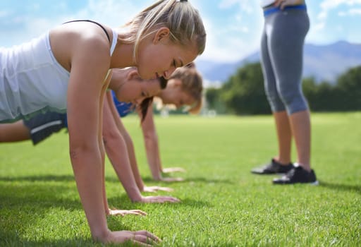 Women, teamwork and push ups on grass for fitness with exercise, training and coach on sports field. Athlete, people and collaboration on ground with physical activity for healthy body and wellness.