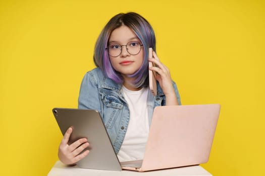 Modern Technology In Daily Life, Teenage Girl Holding Laptop, Tablet Pc, And Mobile Phone. Isolated On Yellow Background, Concept Of Tech-Savvy Lifestyle, Devices Seamlessly Integrate Into Daily Activities.