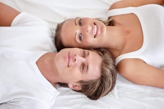Man, woman and portrait in bed for relax waking up from above for relationship care, romance or weekend. Happy partnership, face and smile in apartment for peaceful holiday or couple, love or rest