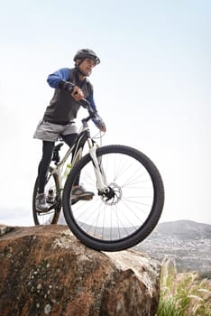 Man, mountain bike and off road cycling on nature adventure or fitness in outdoor extreme sport. Male person or cyclist on bicycle for cardio or dirt path terrain on cliff for exercise with blue sky.