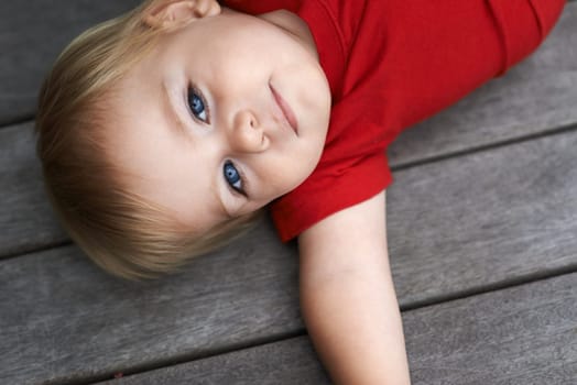 Baby, playing on floor outdoor for development with portrait, curiosity or early childhood in backyard of home. Toddler, child and relax on ground for wellness, milestone and exploring or aerial view