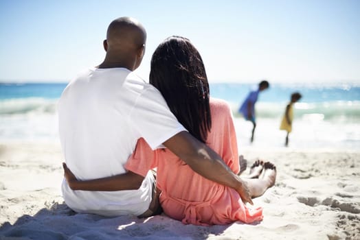 Black family, relaxing on beach and hug with back, sand and married for summer vacation. African, resting and happy for holiday, children and seaside in outdoor, beautiful and day off in ocean