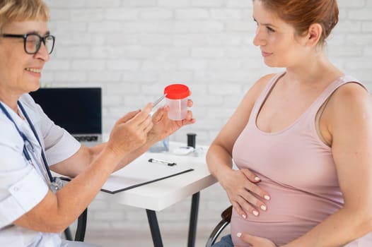 The doctor explains to a pregnant patient how to pass a urine test.