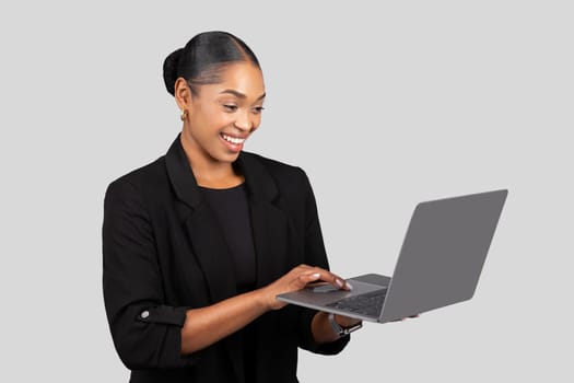 Focused African American businesswoman working on a laptop with a pleased expression