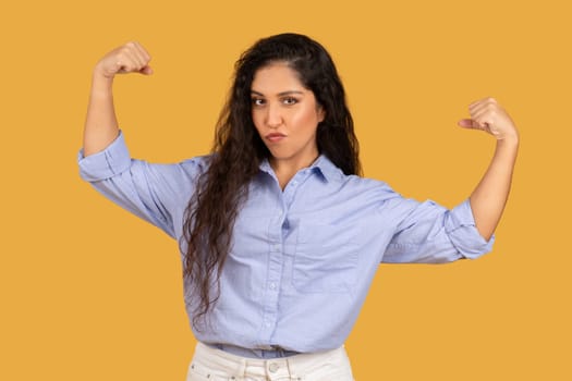 Strong, confident woman with wavy hair showing her muscles in a power pose