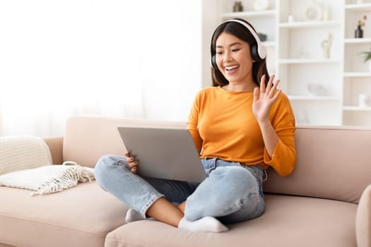 Positive chinese lady have online meeting with family, home interior