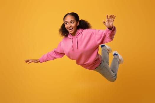 Happy carefree African teenager girl in casual flying in studio