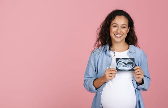 Pregnant woman holding ultrasound image of baby
