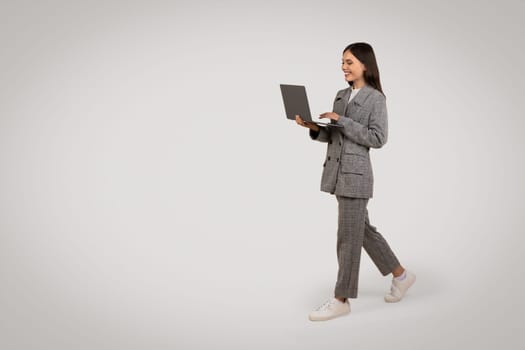 Businesswoman walking with laptop, smiling, copy space