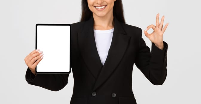 Businesswoman showing digital tablet blank screen, app interface and ok sign, mockup