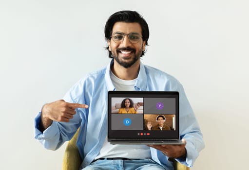 Cheerful indian man showing laptop with video call screen