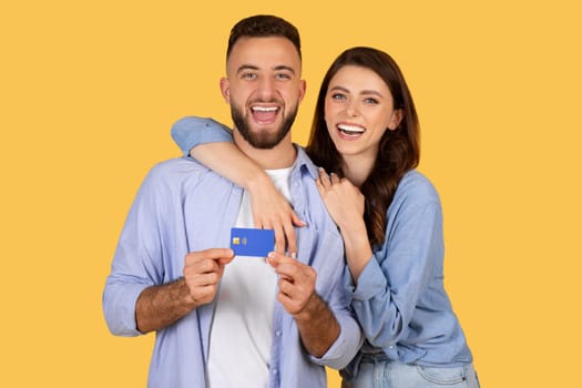 Laughing couple holding credit card, ready for joyful purchase