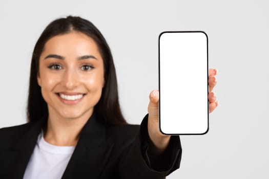 Happy business lady in suit, showing smartphone with empty screen, recommendation for work, study and business app