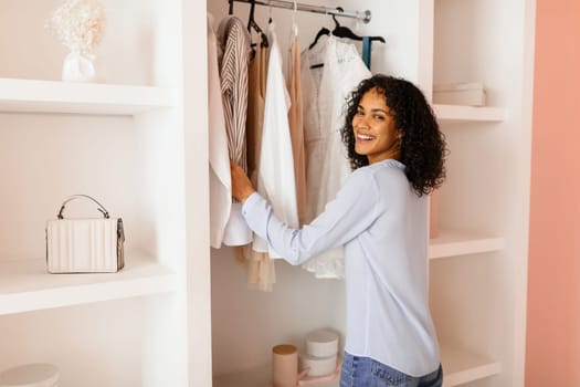 Smiling woman selecting clothes from a neat closet