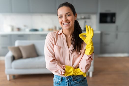 Cheerful woman in gloves ready for spring cleaning at home