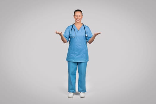 Smiling female doctor wearing blue medical uniform coat and stethoscope talking to camera, explaining and gesturing