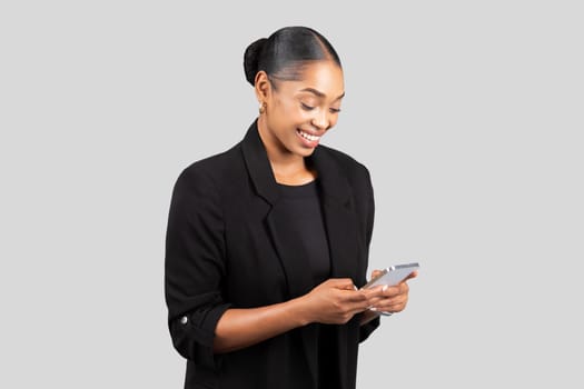 A content young professional woman in formal attire is engrossed in her smartphone