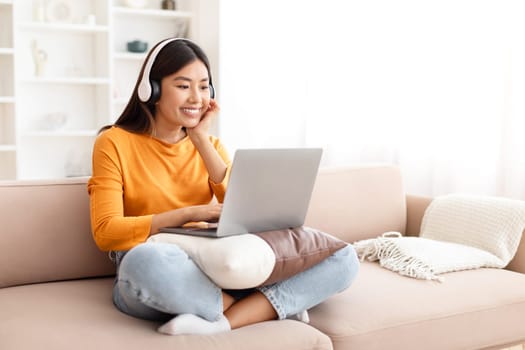 Relaxed young asian woman watching movie on laptop