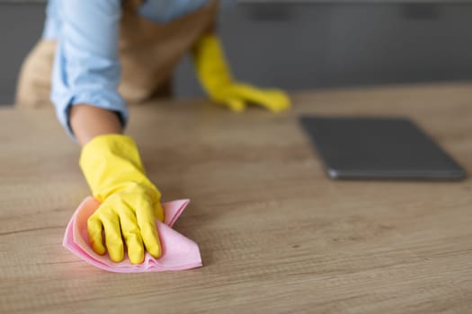 Closeup of hand in yellow glove cleaning with cloth