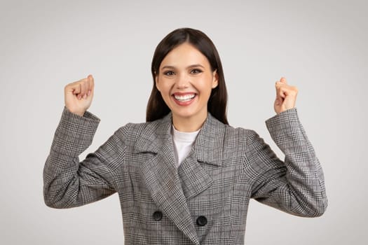 Joyful woman in checkered coat with fists pumped in victory