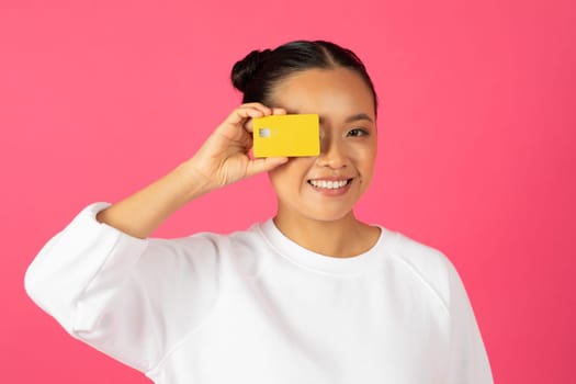 Easy Payments. Cheerful Young Asian Woman Covering Eye With Credit Card