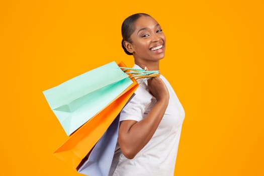 Portrait of happy black woman posing with shopper bags packages