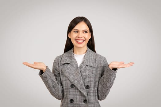 Woman in plaid coat, hands raised, weighing options with a smile