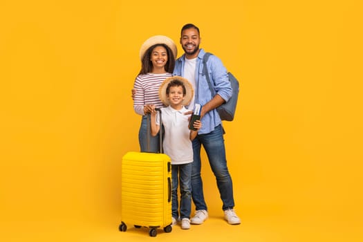 Happy african american family of three with suitcases and travel documents