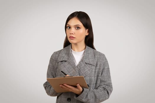 Focused woman with clipboard, serious about her work