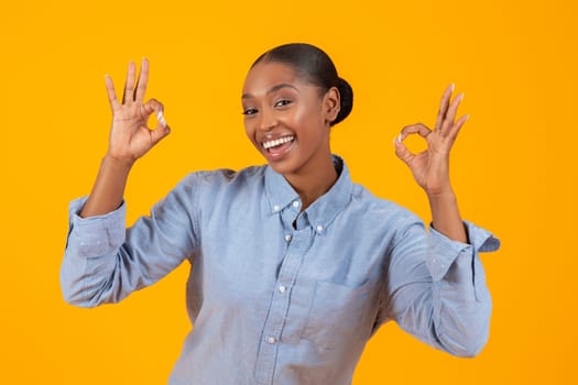 black woman showing OKAY with both hands on yellow backdrop