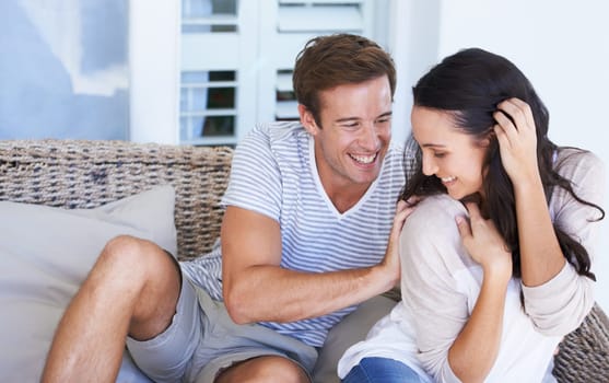 Love, smile and couple tickle on sofa at home, bonding and fun together. Happy man, woman and play in living room for romance, marriage and relax on couch on valentines day in apartment or house