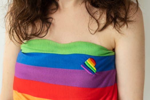 Close-up of a girl wearing a rainbow tube top with a small rainbow ribbon attached to the fabric. LGBT support.
