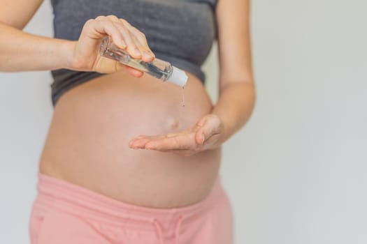 Expectant mom ensures safety, applying gel sanitizer for a clean and healthy pregnancy