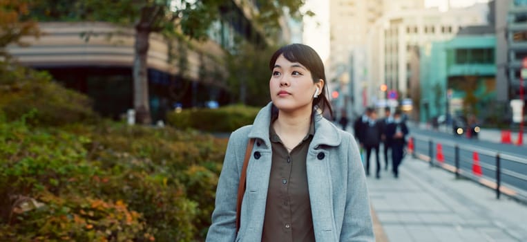 Woman, Asian and walking, travel or commute to work with professional in city with earphones. Listening to music on journey, podcast and commuter on urban street or sidewalk in Tokyo with playlist.
