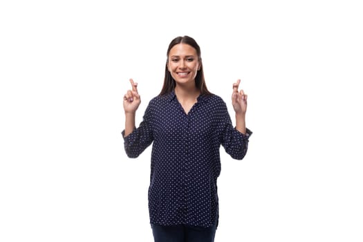 young cheerful cute caucasian brunette lady dressed in a dark blue blouse crossed her fingers