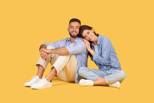 Relaxed couple sitting on floor, woman leaning on man's shoulder