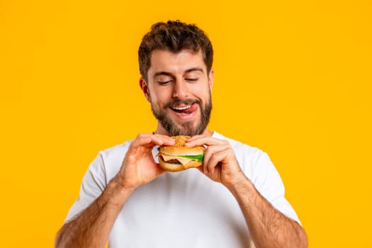 Portrait Of Funny Hungry European Man Eating Tasty Cheeseburger