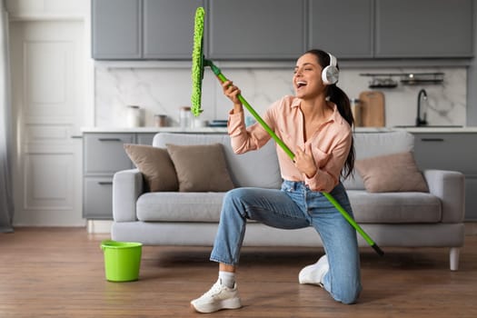 Woman playfully using mop as a guitar while cleaning
