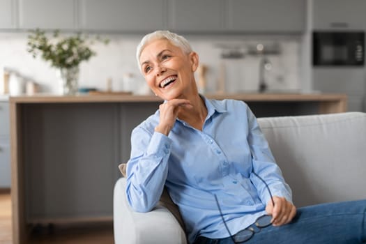senior lady with stylish short haircut laughing sitting on couch