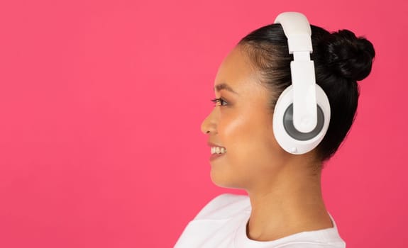 Side view of young asian woman wearing stylish wireless headphones