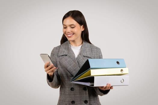 Multitasking woman with smartphone and colorful binders, organized