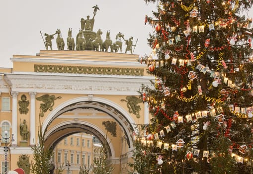 The main Christmas tree shimmers with lights of decorations, the central Palace square of the city decorated for the celebration during the snowfall, Arch of the General Staff, flag of Armed Forces