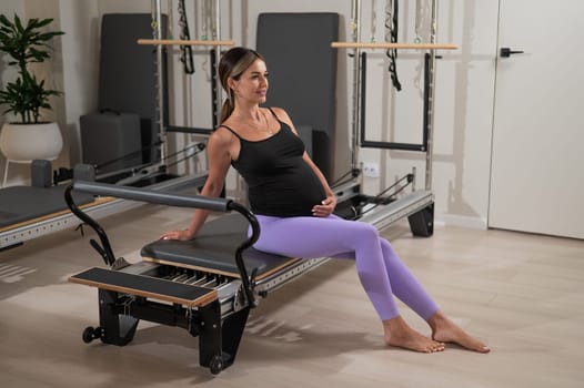 Pregnant woman resting after Pilates on a reformer machine.
