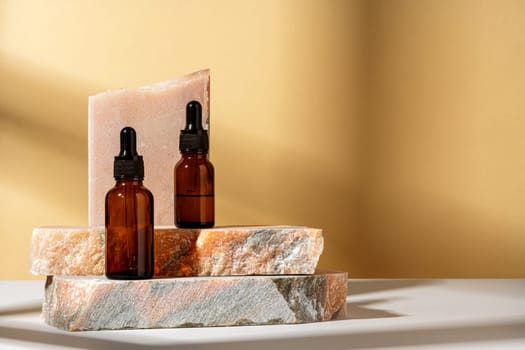 Cosmetic serum in an amber glass bottle with dropper lid with granite stone for composition
