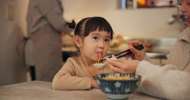 Family, japanese and woman feeding daughter in kitchen of home for growth, health or nutrition. Food, girl eating in Tokyo apartment with mother and grandparent for diet or child development
