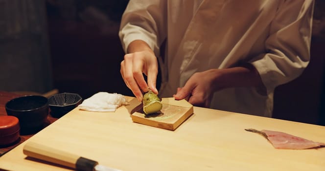 Hands, cooking and wasabi with sushi chef in restaurant for traditional Japanese cuisine or dish closeup. Kitchen, salmon roll or seafood preparation and person working with gourmet meal ingredients.