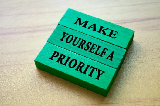 Make yourself a priority text on green color wooden blocks. Aspiration quote.