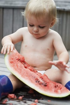 Baby, playing with watermelon and eating, backyard and development with growth, curiosity and home. Toddler, child and infant in garden, alone and childhood for wellness, milestone and coordination